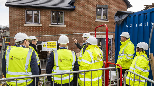 9 people stood in a safe spot discussing the construction