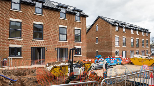 A shot from the ground of a row of houses with lots of windows and construction work outside