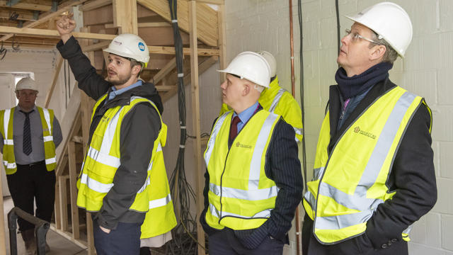 Midland Heart staff wearing high vis jackets and hard hats, taking a look inside a house